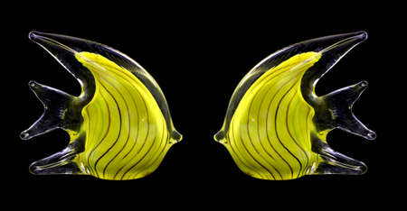Two yellow glass fish against a black background. の写真素材