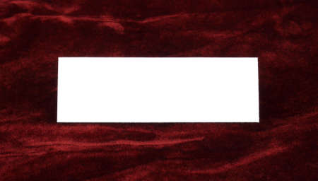 A single brilliant white invitation card sitting on red crushed velvet.の写真素材