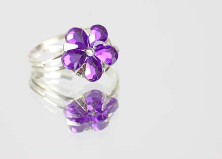 A purple imitation stone costume jewelry ring on a mirrored surface.の写真素材