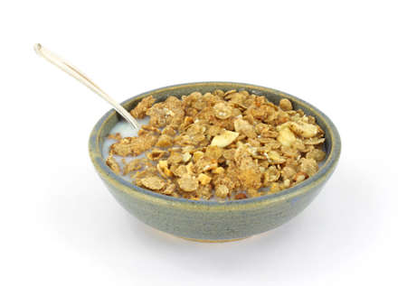A serving of banana and nut granola cereal with skim milk and a spoon on a white background.