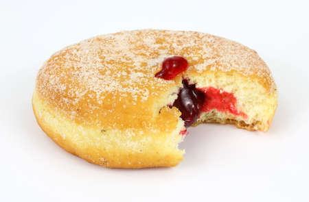 A bitten freshly baked raspberry filled donut with sugar sprinkled on the surface. の写真素材