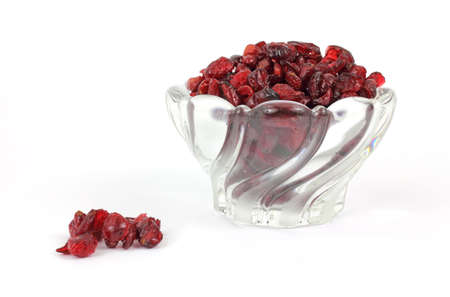A bowl of sweetened dried cranberries with several loose berries in the foreground.の写真素材