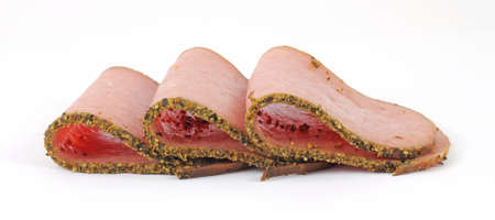 Three slices of deli fresh turkey pastrami that have been folded in half on a white background.の写真素材