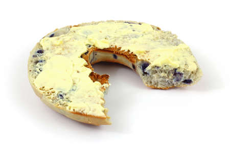 A single blueberry bagel that has been buttered and bitten on a white background.の写真素材