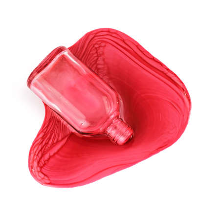 A small bottle of red nail polish spilled on a white background.の写真素材
