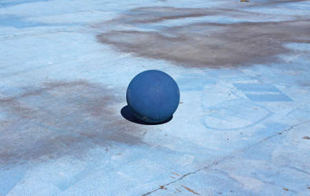 An old basketball on a blue painted concrete court surface.の写真素材