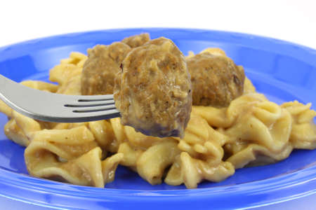 A freshly cooked meatball and pasta dinner on a blue picnic plate.の写真素材