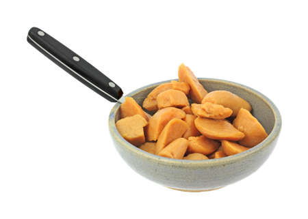 A large serving of cut canned yams in an old bowl with spoon on a white background.の写真素材