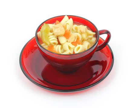 A red cup filled with chicken rotini pasta vegetable soup on a white background.の写真素材