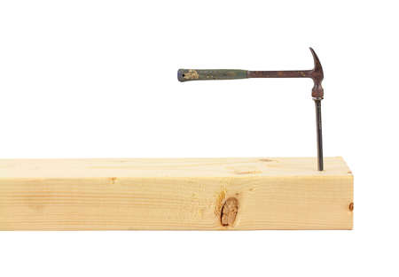 A wood stud with a large nail and a small hammer.の写真素材