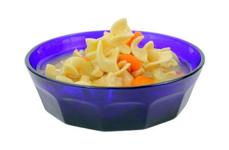 Chicken soup with pasta and carrots in a blue bowl.の写真素材