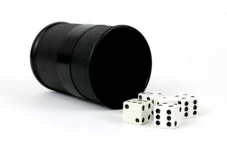 A black playing cup with several dice in the foreground.の写真素材