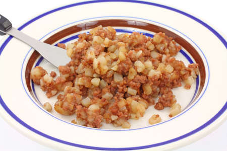 A fork filled with corned beef hash above a plate.の写真素材