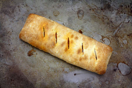 A single hot pizza sandwich on a well used baking pan.の写真素材