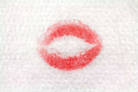 Close view of the print of woman's red lipstick that has been blotted on a white napkin.の写真素材