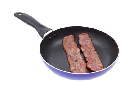 Two pieces of turkey bacon cooking in a skilletの写真素材
