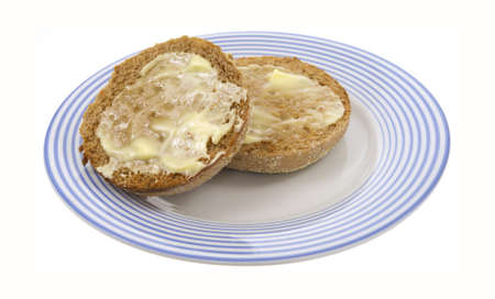 An English muffin that has been toasted and buttered on a blue striped plate. の写真素材