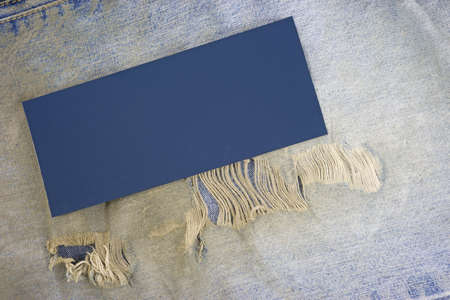 Close view of an old pair of bluejeans that are dirty and worn with a blue patch next to the frayed holes.の写真素材