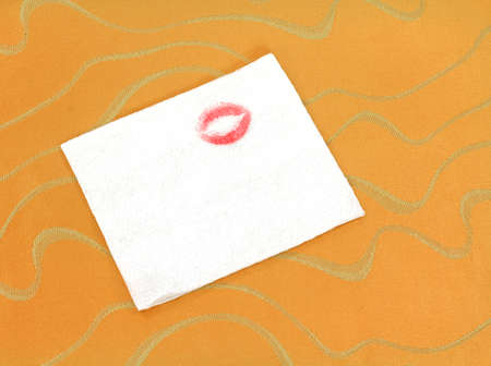 A white napkin that has been blotted with red lipstick on a gold fabric cloth. の写真素材