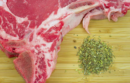 A very close view of part of a t-bone steak with seasoning on a wood cutting board.の写真素材