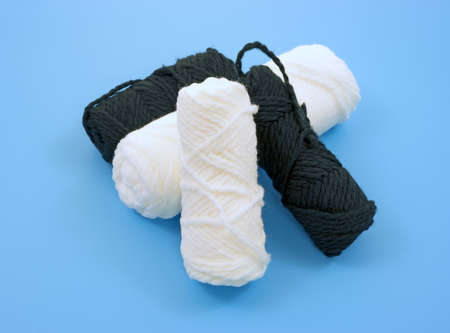 Four skeins of white and black yarn on a blue background.