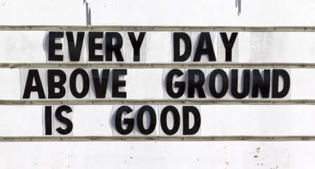 A roadside sign stating Every Day Above Ground Is Good 
