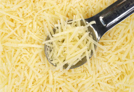 Close view of shredded Parmesan cheese with a small measuring spoon  の写真素材