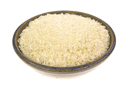 An old bowl filled with flaked panko style bread crumbs on a white background の写真素材