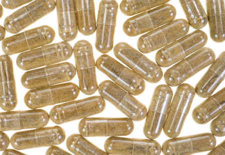 Close view of a layer of green tea extract capsules on a white background 