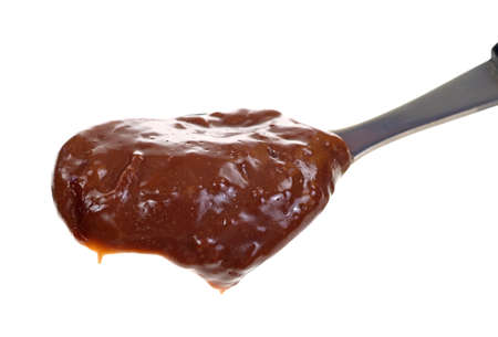 Close view of a spoon full of chocolate pudding on a white background 