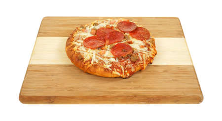 A freshly cooked personal size thick pan pizza on a wood cutting board の写真素材