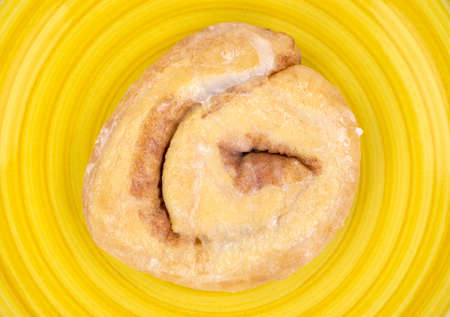 Close view of a honey bun on a bright yellow plate の写真素材