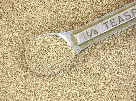 Close view of organic active dry yeast with a very old and worn measuring spoon の写真素材