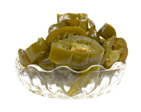 A bowl filled with sliced processed jalapeno peppers on a white background の写真素材
