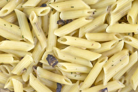 A very close view of freshly cooked penne pasta with mushrooms and parsley.の写真素材