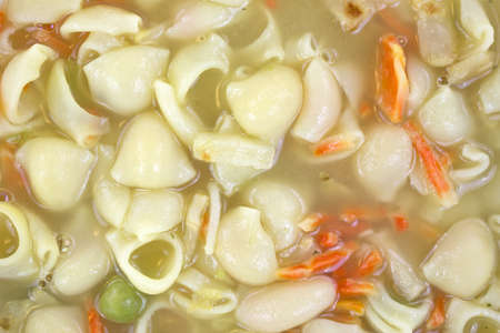 A very close view of chicken broth soup with pasta and vegetables.の写真素材