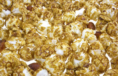 A layer of caramel popcorn with peanuts strewn onto a white background.の写真素材