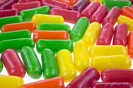 Several pieces of fruit flavored chewing gum atop a white background.の写真素材