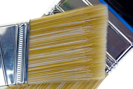 Close view of a sash paint brush atop a wider brush showing the bristles 