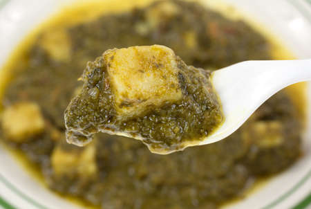 A fork full of pureed spinach with a single chunk of white potato in the foreground with the...