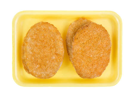Top view of several pre-cooked frozen veal patties on a yellow butchers tray.の写真素材