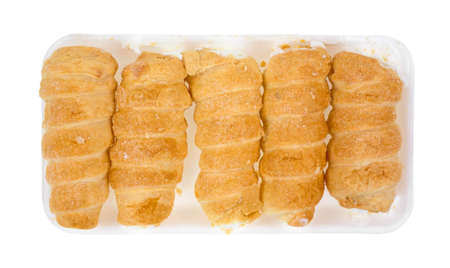 Five freshly baked cream horns on a white foam tray 