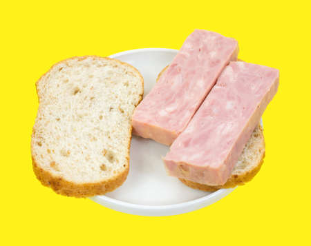 Two thick slices of processed ham on bread in plate atop a bright yellow background の写真素材