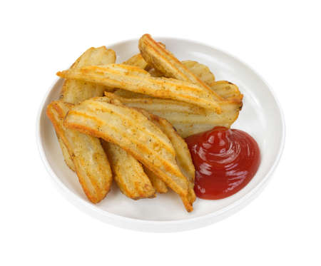 A serving of cooked potato wedges in small dish with ketchup 