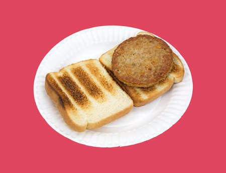 A cooked veggie burger on white bread toast atop a paper plate against a red background 