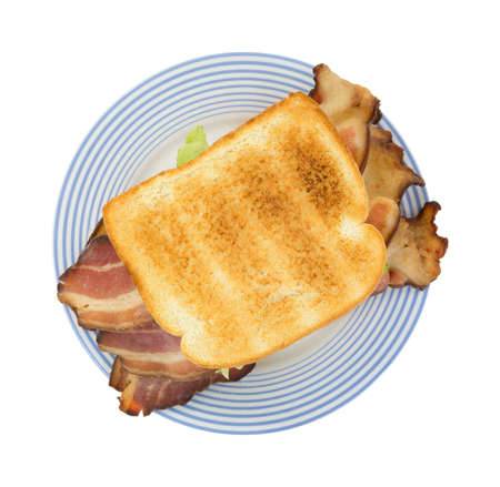 Top view of a large bacon sandwich with lettuce on an old blue striped plate の写真素材