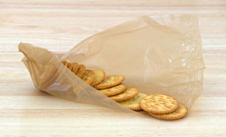 An opened package of snack crackers in packaging on a wood counter top 