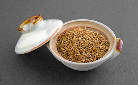 A small bowl with separate lid of anise seeds on a dark background の写真素材