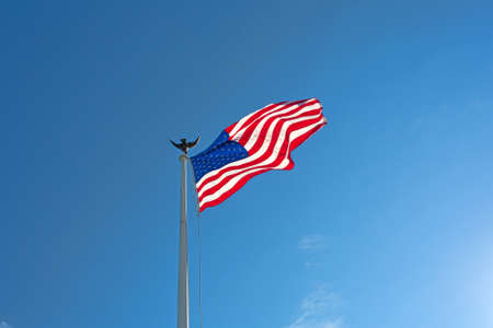 The American flag flapping in the wind against a blue sky with wispy clouds の写真素材