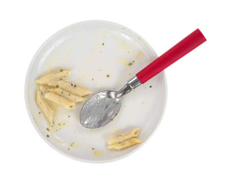 Top view of a plate of pasta that has been eaten with a red handled spoon on a white の写真素材